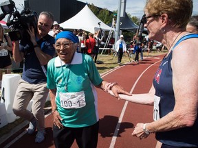 Man Kaur, left, 100, of India, is helped by another runner after competing in the 100-metre track and field event at the Americas Masters Games in Vancouver, B.C., on Monday August 29, 2016. Kaur, who completed the race in just under 1 minute and 22 seconds, already won gold medals in shot put and javelin events. More than 10,000 athletes aged 30 and older are participating in the games which continue until September 4.