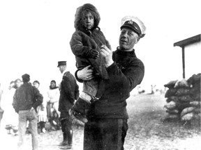 Henry Larsen holding an Inuit child. Two other crew members and several Inuit women are standing in the background. Photo: VMM PARKS CANADA / HCRO-20-13 ca. 1944
