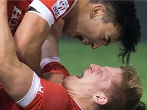 Canada's Nathan Hirayama, top, and John Moonlight celebrate after Moonlight scored the winning try in the final moments of play against France during World Rugby Sevens Series' Canada Sevens Bowl final action, in Vancouver, B.C., on Sunday March 13, 2016.