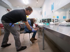 Clinic assistant Patrick Keeler assists Tracey Loyer after she finishes injecting hydromorphone at the Providence Health Care Crosstown Clinic in Vancouver’s Downtown Eastside earlier this year, where in the midst of a public health crisis not one participant has died of an opioid-related overdose.