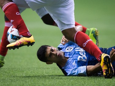 Vancouver Whitecaps' Matias Laba, back, falls to the ground after colliding with San Jose Earthquakes' Quincy Amarikwa, as he gains control of the ball, during the first half of an MLS soccer game in Vancouver, B.C., on Friday August 12, 2016.