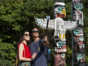 Eduardo Ferreira and Erica Andrade, tourists from Brazil, take a selfie photo at Vancouver's Stanley Park totems.