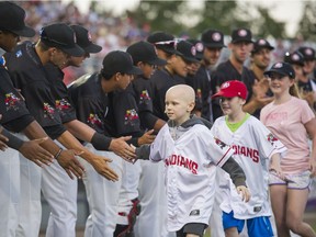 Connor Morcom ( L ) followed by Carter Milaney ( C ) and Olivia Milaney ( R ) low five Vancouver Canadian players after running the basesLduring Childhood Cancer Awareness Night at Nat Bailey stadium, Vancouver, August 17 2016.