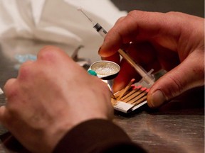 A man prepares heroin he bought on the street to be injected.