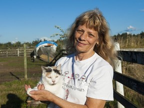 Sandra Simans holds a cat Tuesday at her property in Langley where 88 animals were seized by the SPCA.