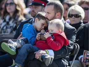 Brad Aschenbrenner, husband of RCMP officer Sarah Beckett, holds his sons Lucas (left) and Emmit during the Canadian Police and Peace Officers' Memorial Service on Parliament Hill. Beckett was killed in a car crash while on duty in Langford, B.C. on April 5, 2016.