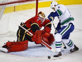 Vancouver Canucks' Jack Skille, right, goes for the puck in front of Calgary Flames goalie Brian Elliott, during second period pre-season NHL hockey action in Calgary, Friday, Sept. 30, 2016.