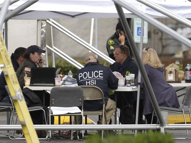Law enforcement officials work under a tent, Saturday, Sept. 24, 2016, outside the Cascade Mall in Burlington, Wash.  Authorities said Saturday several people were dead after the shooting Friday night and the suspect was still at large. The identity of the suspect, his motive and how he got a rifle into the mall remained unanswered.