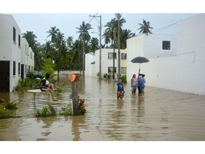 Local residents stand on the flooded street outside their houses in Campestre La Laguna, Acapulco, Mexico during heavy rains that lashed the country's Pacific coastal region on September 4, 2016, causing flooding and evacuation of families to temporary shelters. /