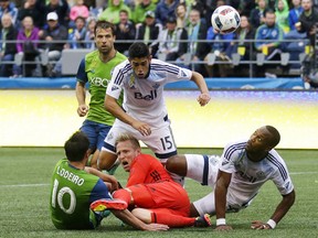 Vancouver Whitecaps goalkeeper David Ousted, lower center, watches the ball during a 1-0 loss to the Seattle Sounders.