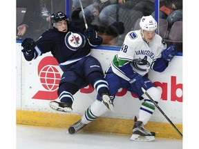 Vancouver Canucks' Olli Juolevi (78) on the boards with  Winnipeg Jets' Antoine Waked (88).