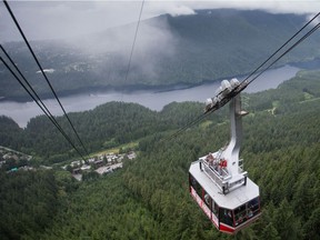 People ride on top of a Grouse Mountain cable car in North Vancouver, B.C., on Friday, July 15, 2016. A special platform was built on top of the car to allow visitors to be outside while ascending the 1,610-metres up the mountainside on the largest tramway system in North America.