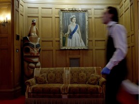 An employee walks by a painting of Queen Elizabeth during event preparations ahead of the upcoming Royal visit to the Government House in Victoria.