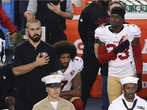 San Francisco 49ers quarterback Colin Kaepernick (middle) kneels during the U.S. national anthem before the team's NFL pre-season game against the San Diego Chargers on Thursday in San Diego.
