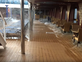 Water from the pool floods the deck of the Carnival Legend after a propulsion failure caused her to make a hard port turn and listed suddenly.