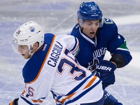 Edmonton Oilers' Drake Caggiula, left, and Vancouver Canucks' Troy Stecher collide.
