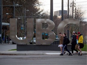 Young men walk past large letters spelling out UBC at the University of British Columbia in Vancouver on November 22, 2015.