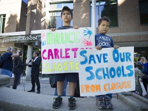 Students Denzell Cheng, left, and his brother Connor join parents and politicians Monday in a protest against possible school closures outside the Vancouver school board offices.