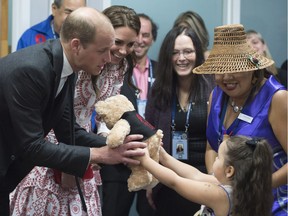 Britain's Prince William receives a teddy bear from five-year-old Hailey Cain as Kate, Duchess of Cambridge, second left, looks on during a tour of Sheway, a center that provides support for native women, during a visit to Vancouver, B.C., Sunday, Sept. 25, 2016. (Jonathan Hayward/The Canadian Press via AP) ORG XMIT: JOHV102