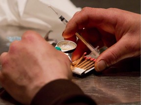 A man prepares heroin he bought on the street to be injected at the Insite safe injection clinic in Vancouver, B.C., on Wednesday May 11, 2011.