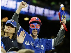 A Toronto Blue Jays fan wears a mask and holds a stuffed parrot as he cheers in the fourth inning of a baseball game against the Seattle Mariners, Tuesday, Sept. 20, 2016, in Seattle.