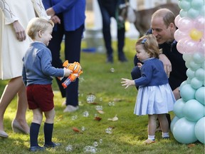 Britain's Prince William and Princess Charlotte look on as Prince George plays with a bubble gun at a children's party at Government House in Victoria, British Columbia, Thursday, September 29, 2016.
