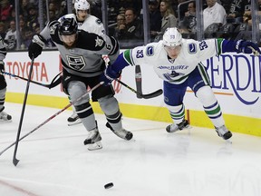 Los Angeles Kings' Jake Muzzin, left, and Vancouver Canucks' Bo Horvat chase the puck during the first period of an NHL hockey game Saturday, Oct. 22, 2016, in Los Angeles.