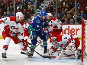 Eddie Lack of the Carolina Hurricanes makes a save on Jannik Hansen of the Vancouver Canucks as Jaccob Slavin and Justin Faulk of the Hurricanes watch during their NHL game at Rogers Arena October 16, 2016 in Vancouver, British Columbia, Canada.