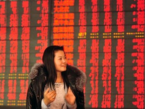 An investor makes her way in front of a screen showing stock market movements in a securities firm in Fuyang, east China's Anhui province on March 2, 2016.