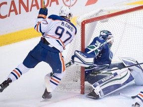 Edmonton Oilers' Connor McDavid, left, scores against Vancouver Canucks' goalie Ryan Miller during the second period of an NHL hockey game in Vancouver, B.C., on Friday October 28, 2016.