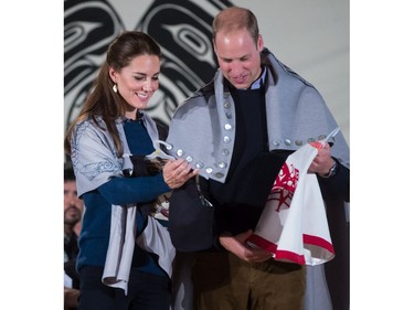 Draped in traditional First Nation blankets, Britain's Prince William, the Duke of Cambridge, and Kate, the Duchess of Cambridge, hold vests they were presented with for Prince George and Princess Charlotte during a welcoming ceremony at the Heiltsuk First Nation in the remote community of Bella Bella, B.C., on Monday September 26, 2016.