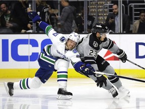 Los Angeles Kings' Dustin Brown, right, is defended by Vancouver Canucks' Philip Larsen, of Denmark, during the second period of an NHL hockey game Saturday, Oct. 22, 2016, in Los Angeles.