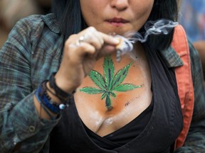 A young woman smokes a joint during a rally calling for the legalization of marijuana.