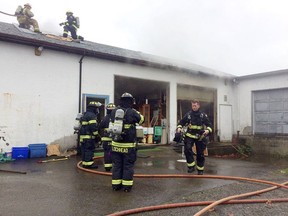 Firefighters open up the roof of Qualicum Beach's Remember That Collectibles on Fern Road after fire broke out Friday morning at about 10:30 a.m. The blaze, which killed one man, was contained.