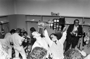 Dressing room of the Pacific Coliseum after the New Westminster Bruins hockey team beat the Ottawa 67’s 6-5 to win the memorial cup. Province photographer Colin Price (with cameras); others to ID. May 15, 1977.