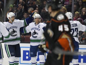 Vancouver Canucks center Henrik Sedin, second from left, of Sweden, celebrates his goal with defenseman Alexander Edler, left, of Sweden, and left wing Daniel Sedin, right, of Sweden, as Anaheim Ducks defenseman Sami Vatanen, of Finland, skates by during the third period of an NHL hockey game, Sunday, Oct. 23, 2016, in Anaheim, Calif. The Ducks won 4-2.