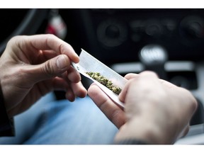 A man rolls a joint while sitting in a vehicle.