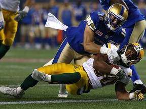Edmonton Eskimos RB John White fights through a tackle from Winnipeg Blue Bombers DB Taylor Loffler for a touchdown during CFL action in Winnipeg on Fri., Sept. 30, 2016.