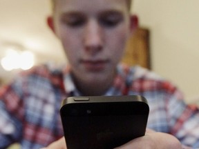 In this Oct. 24, 2013 photo, Mark Risinger, 16, checks his smartphone at home in Glenview, Ill.