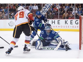 Vancouver Canucks' goalie Ryan Miller, right, stops Calgary Flames' Micheal Ferland, left, as Canucks' Philip Larsen, back, of Denmark, defends during the first period of a pre-season NHL hockey game in Vancouver, B.C., on Thursday October 6, 2016.