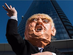 A man wearing an oversized Donald Trump head protests outside the still under construction Trump International Hotel and Tower, during demonstration to encourage U.S. expats across Canada to register and vote, in Vancouver, B.C., on Wednesday October 5, 2016.
