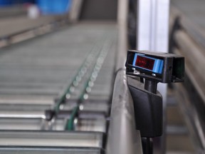 A roller conveyor with a laser distance sensor on the side. Smaller and faster sensors, tied to more powerful computers, are revolutionizing industrial processes.