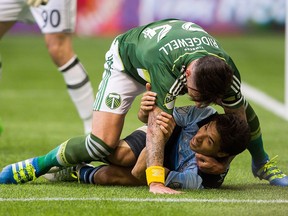 Vancouver Whitecaps' Nicolas Mezquida (11) is taken to the ground by Portland Timbers' Liam Ridgewell during a game at B.C. Place in 2016.