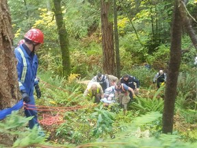 Sooke Fire Department's rope rescue team lifts Pat Hauser from a Metchosin ravine on Sunday, with assistance from the Metchosin Fire Department and West Shore RCMP. Hauser spent two nights trapped outdoors in the woods on a stormy weekend after going missing on Friday. He remained in hospital on Monday in stable condition. [PNG Merlin Archive]