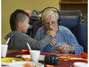 Five-year-old Tony Han Jr. lends a helping hand to 100-year-old Alice Clark at Youville Residence care facility in Vancouver.