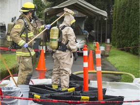 A first responder in a haz-mat suit is washed down by a firefighter at a decontamination station after leaving a home where firefighters found evidence suggesting the presence of a drug lab.