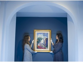 Julia Balazs ( L ) and Kate Galicz  adjust a painting by Emily Carr that is part of Peter Brown art collection for sale at the Heffel Fine Art Auction House,
