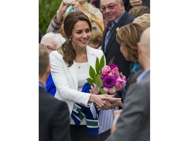 Kate, Duchess of Cambridge holds onto a bouquet of flowers and a Vancouver Canucks jersey for Prince George of Cambridge while visiting the Cridge Family Centre in Victoria, BC, October, 1, 2016.