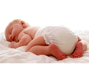 A baby in diapers sleeping on a blanket.