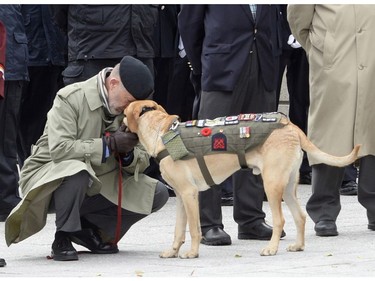 A veteran hugs his service dog during a Remembrance Day ceremony at the National War Memorial in Ottawa on Friday, Nov. 11, 2016.